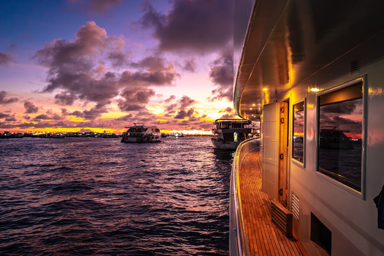 Home Stunning sunset over the Maldives with luxury yachts cruising the calm waters.